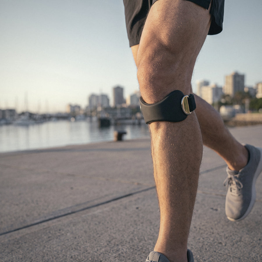 Runner on a waterfront path wearing the OXYFIT Patella Strap