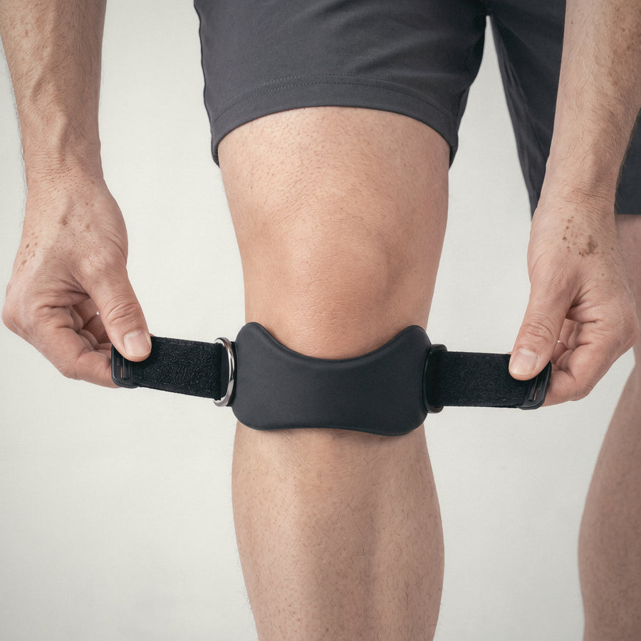 Hands pulling the OXYFIT Patella Strap snug below the kneecap