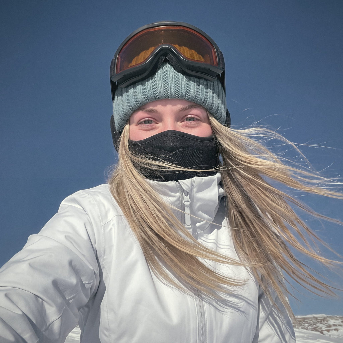 Woman taking a selfie on a sunny winter day wearing the Face Guard